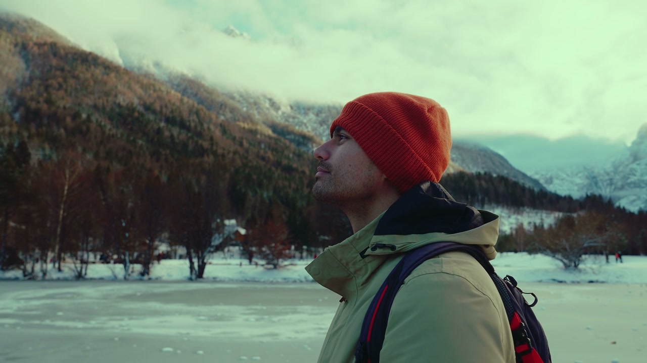 Man Looks Up at Snowy Mountains by Frozen Lake Jasna
