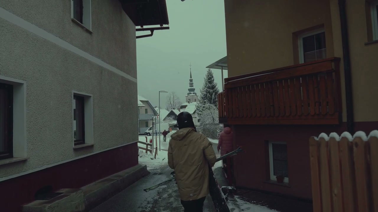 People Carrying Skis Down Snowy Village Street