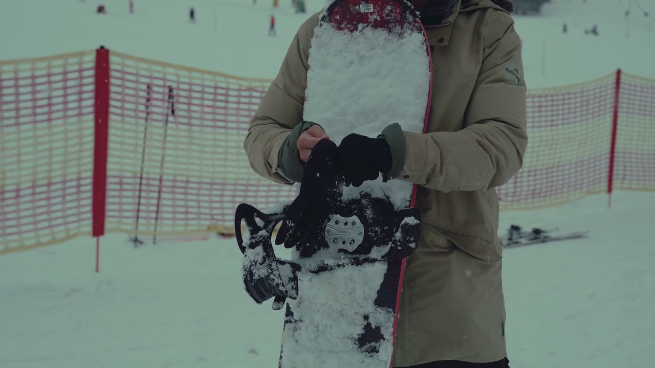 Snowboarder Adjusting Binding On Mountain