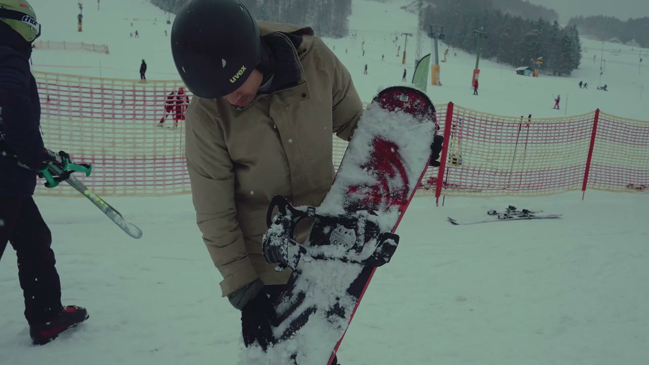 Person Strapping into Snowboard Bindings