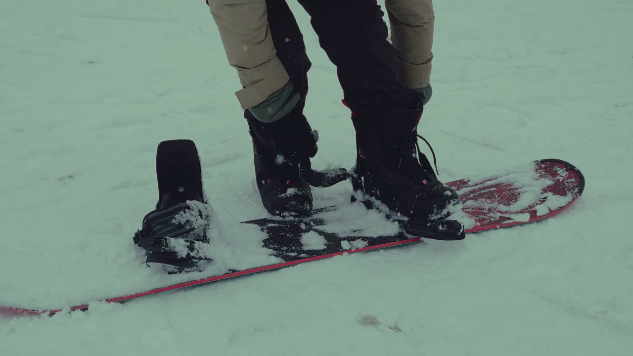 Snowboarder Strapping into Bindings