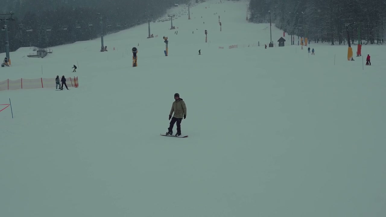 Person Snowboarding Down a Snowy Ski Slope