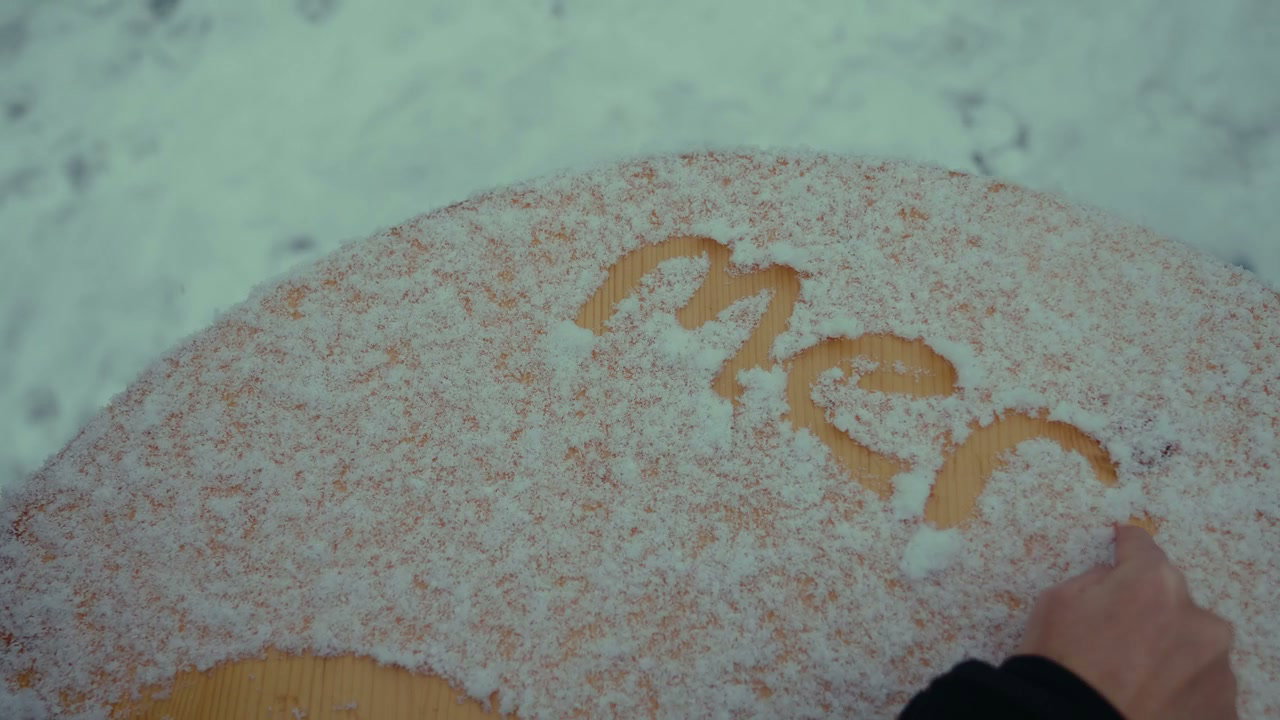 Hand Writing Merci in Snow on Table