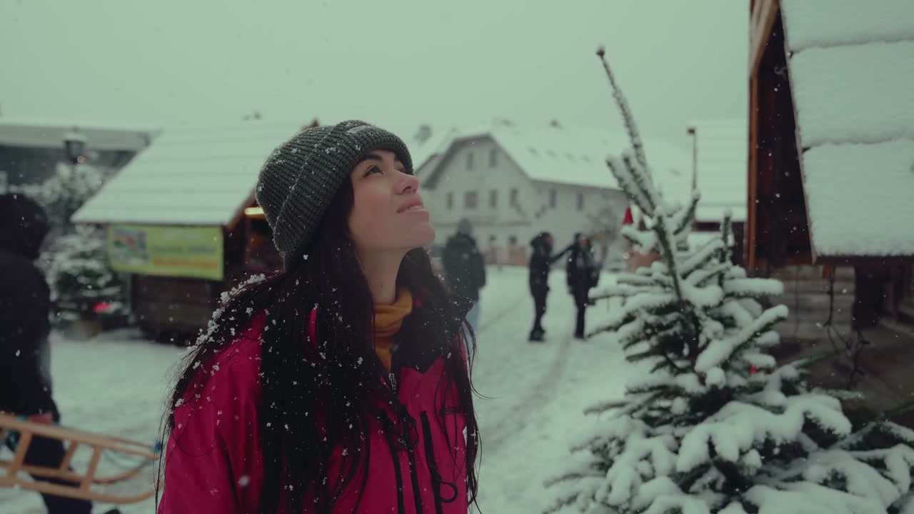 Young Woman Catching Snowflakes in Winter Village