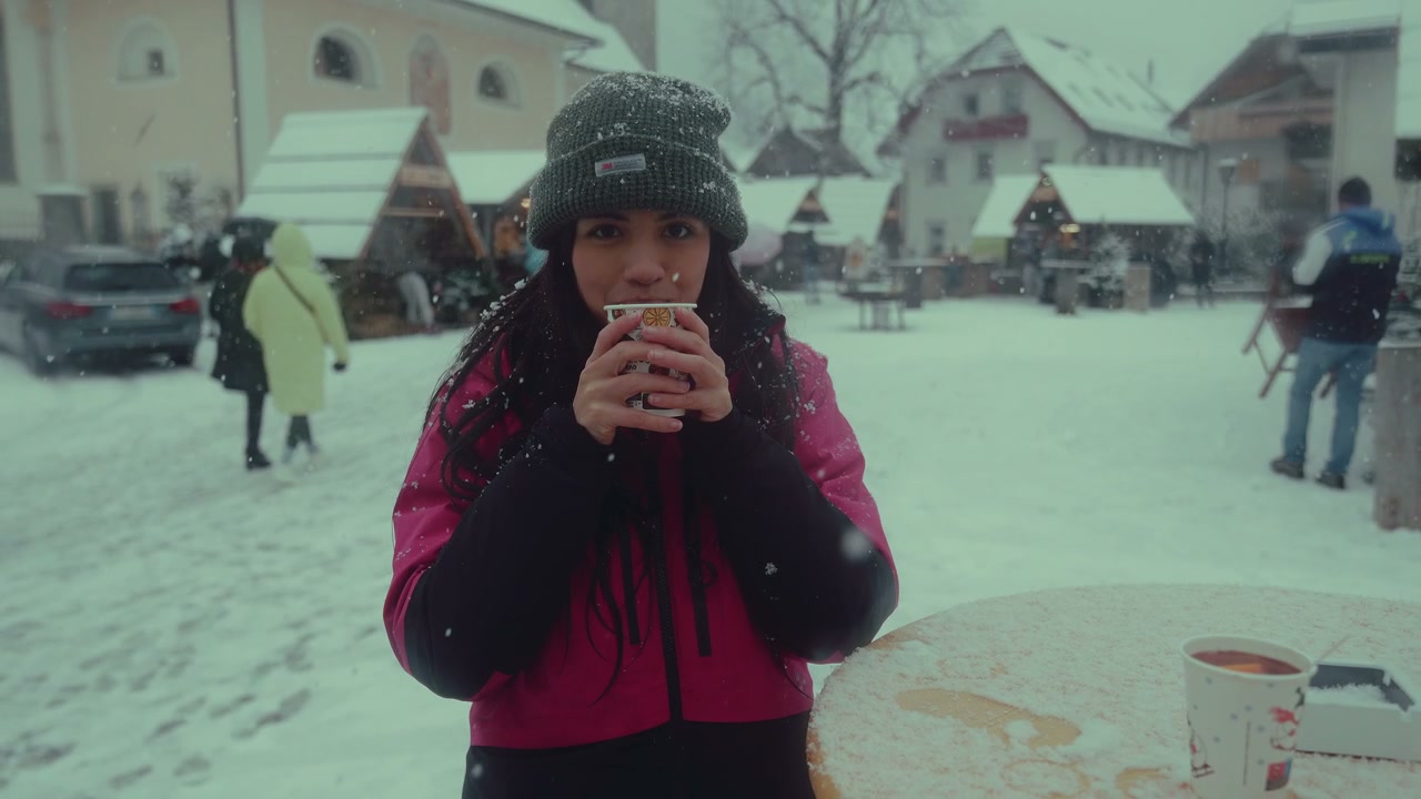 Person Drinking Hot Beverage in Snowy Town Square
