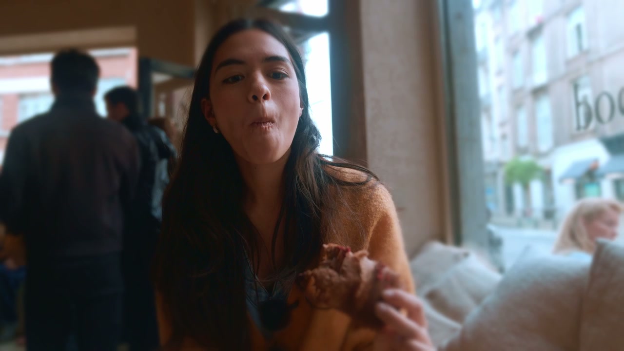 Woman Eating Croissant in Brussels Cafe