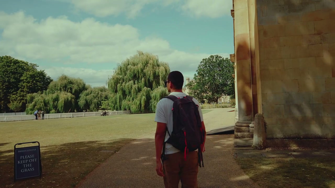 Man with Backpack Walking Through Cambridge Grounds