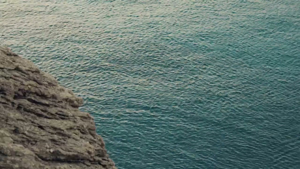 Blue Sea Water Rippling Next to Cliff
