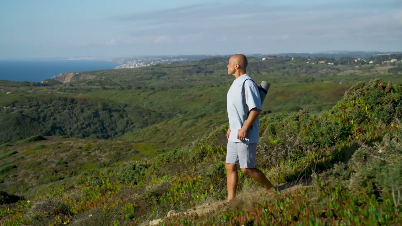 Person Walking with Yoga Mat on Ocean Clifftop