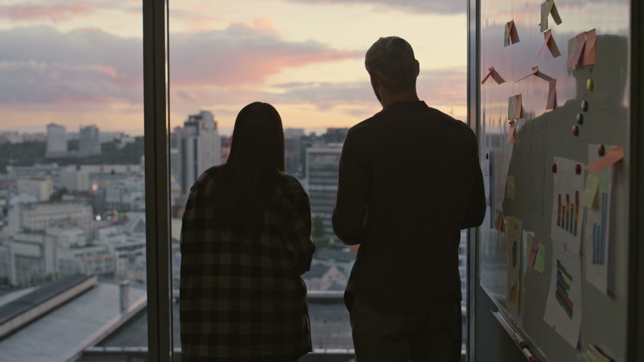 Coworkers Discussing Whiteboard in Office at Sunset