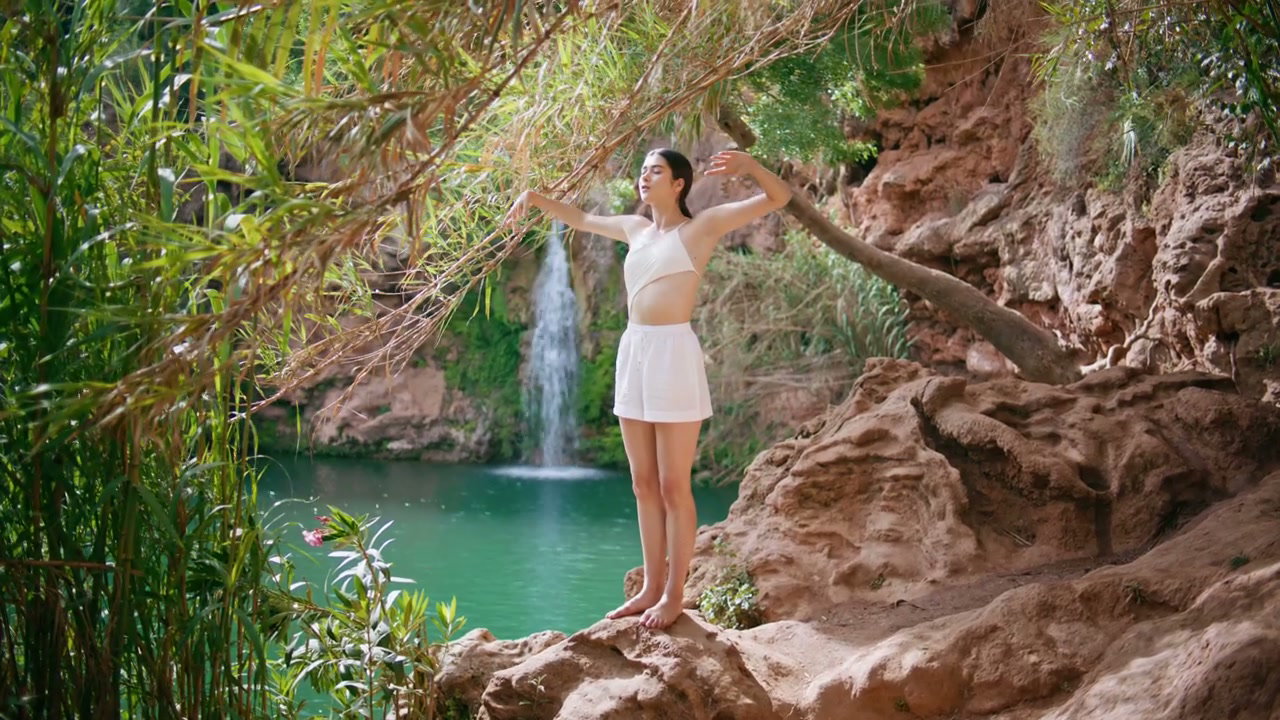 Woman Stretching by Tropical Waterfall