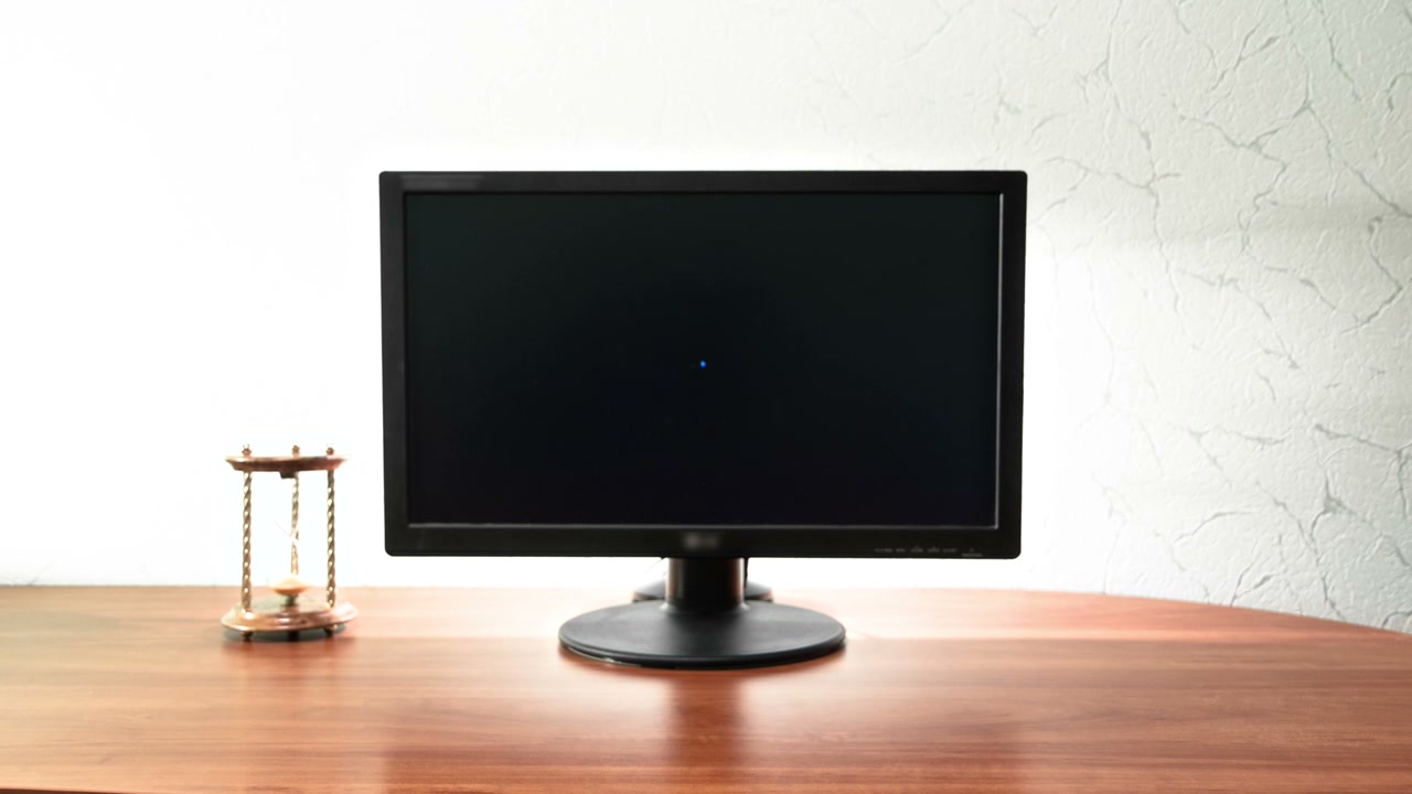 Hourglass on Desk with Black Monitor