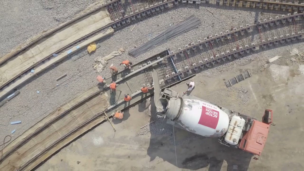 Construction Workers Pouring Concrete on Railway Tracks