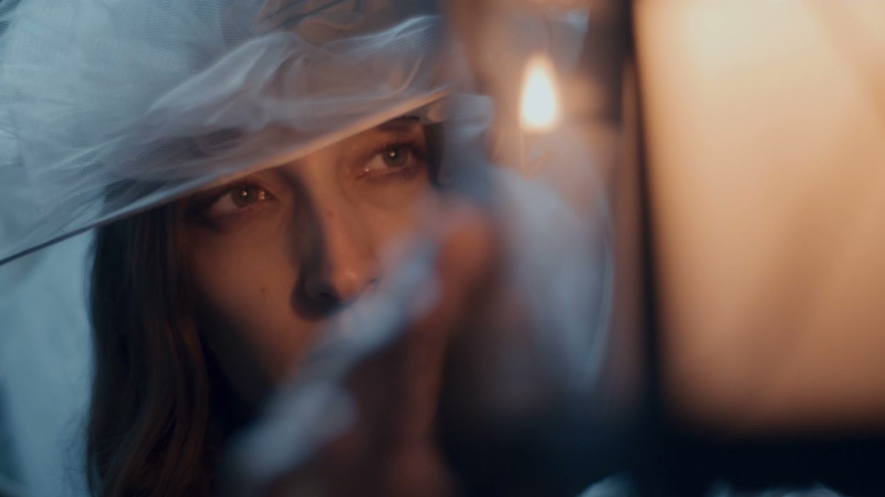 Woman in Veil Looking at Candlelight