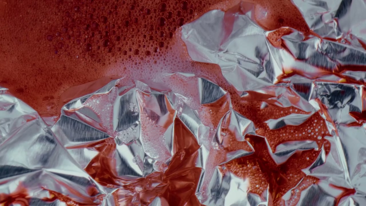 Red Liquid Flows Over Crumpled Silver Foil