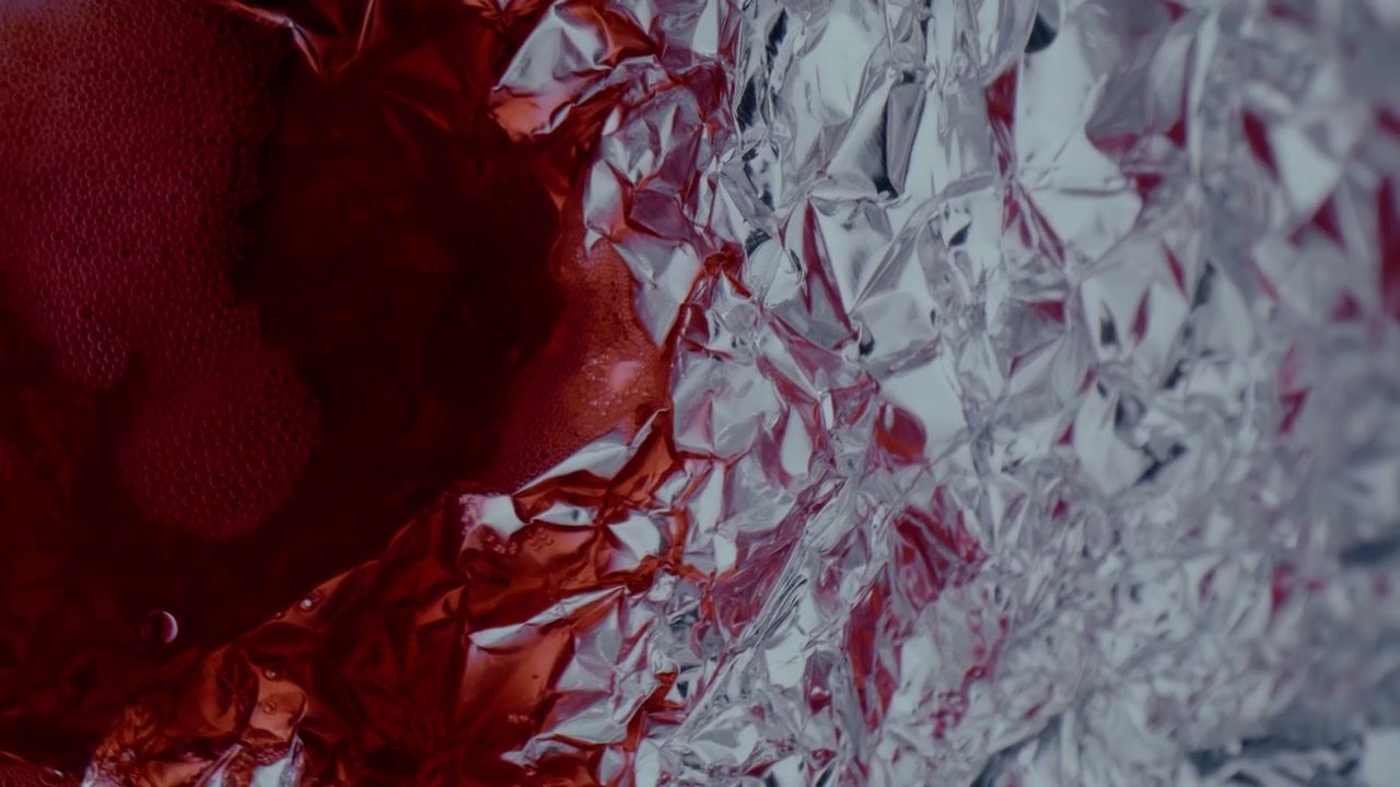 Abstract Red Liquid Spreading on Crinkled Foil