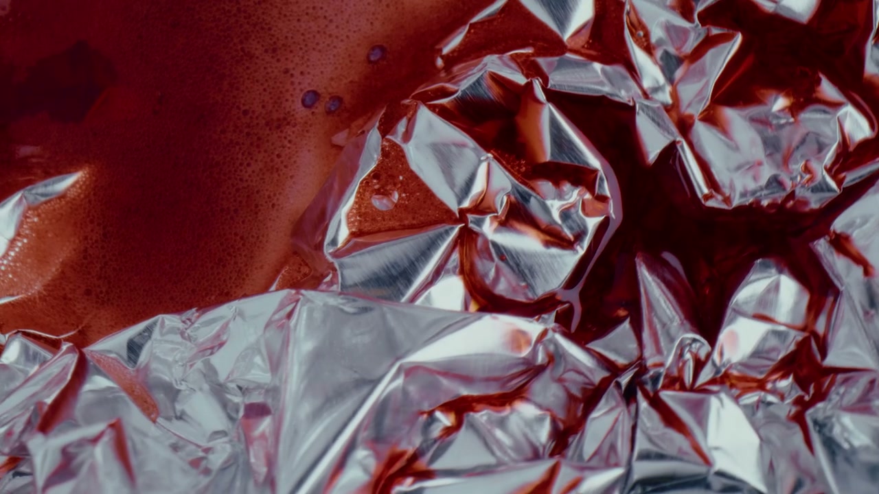 Abstract Red Fluid Flowing on Silver Foil
