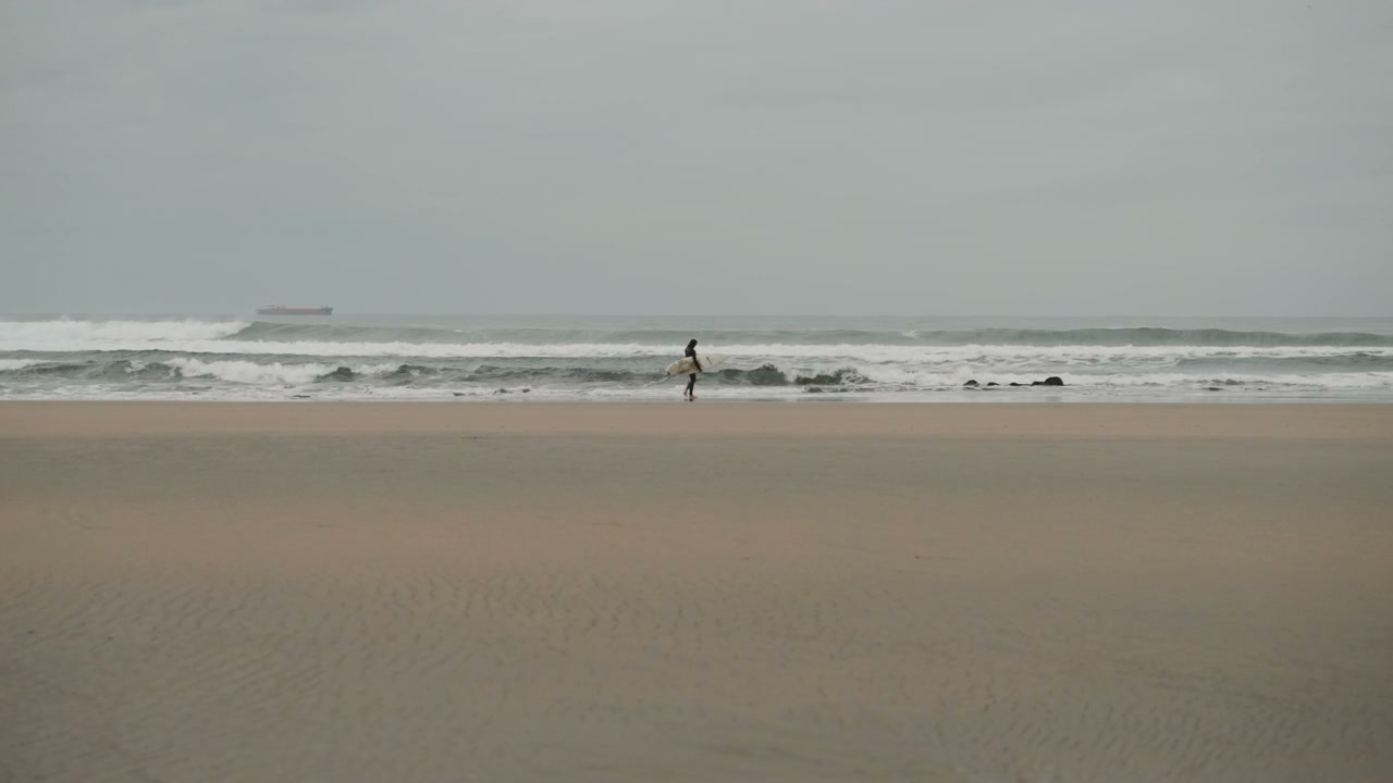 Surfer Walking on Beach with Surfboard