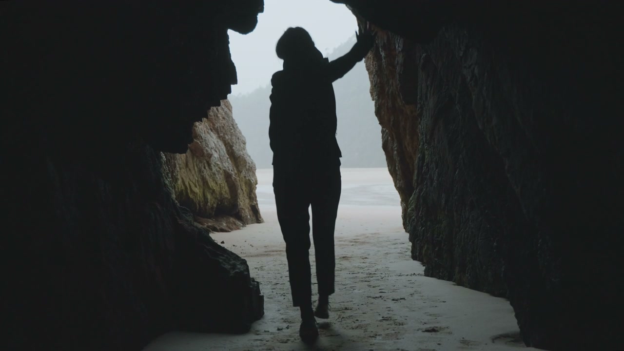 Person Walking From Cave To Coastal Beach