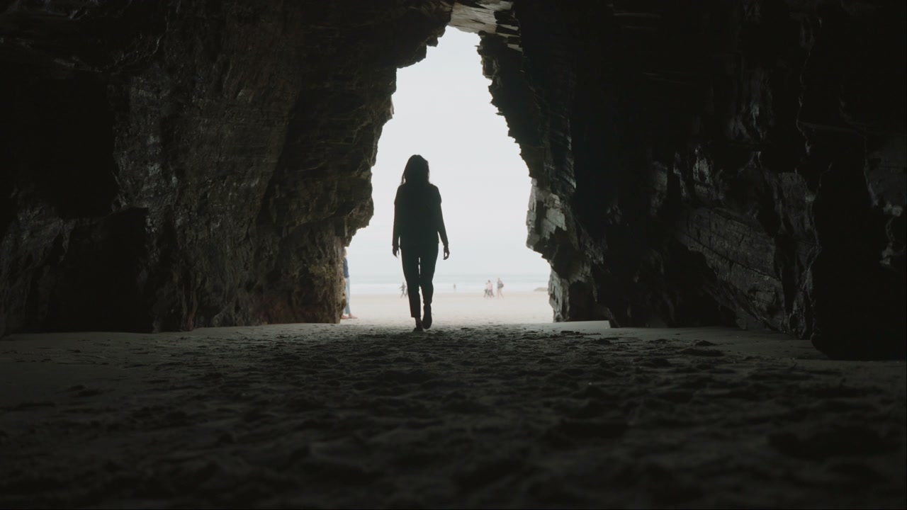 Silhouette Walking from Cave to Beach