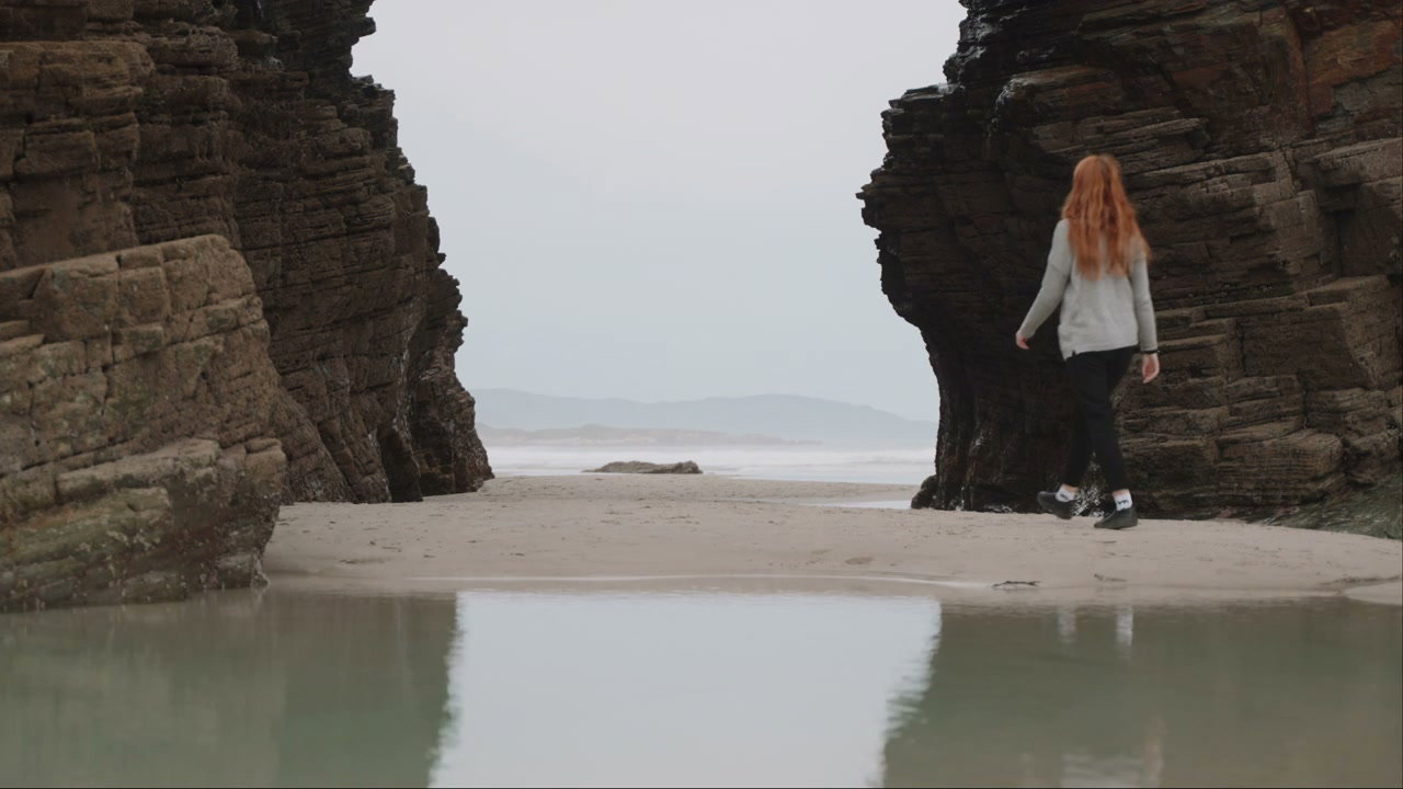 Person Walks Between Coastal Rock Formations