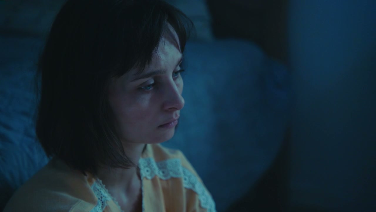 Sad Woman Looking Towards Camera in Dark Room