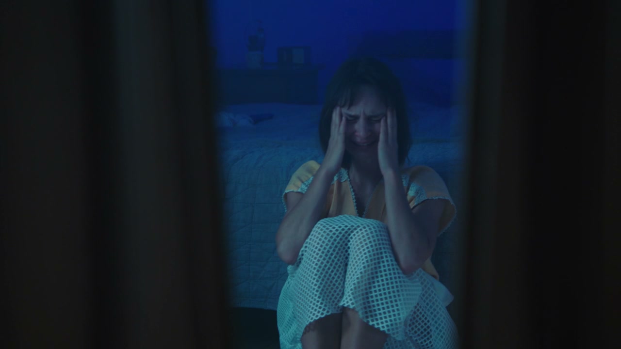 Young Woman Crying in Dark Bedroom
