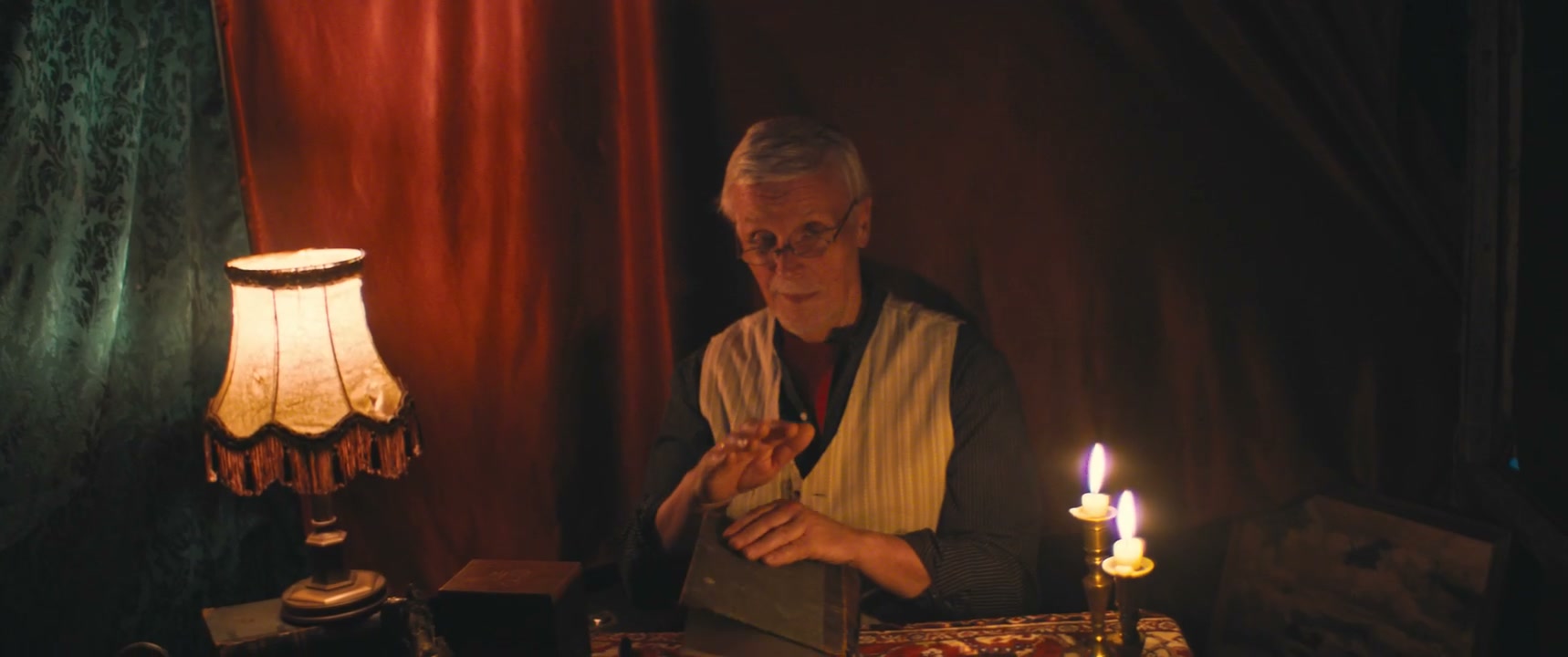 Older Man Reads Book by Candlelight