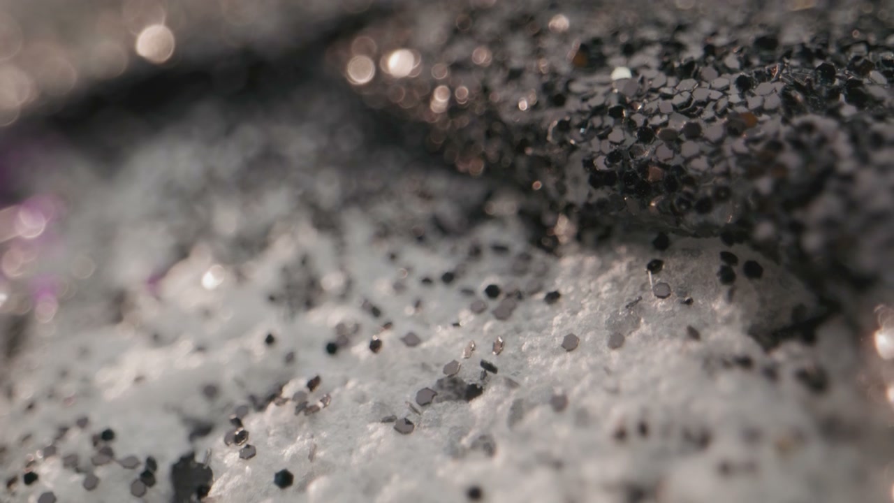 Black Glitter Spreading on White Textured Surface