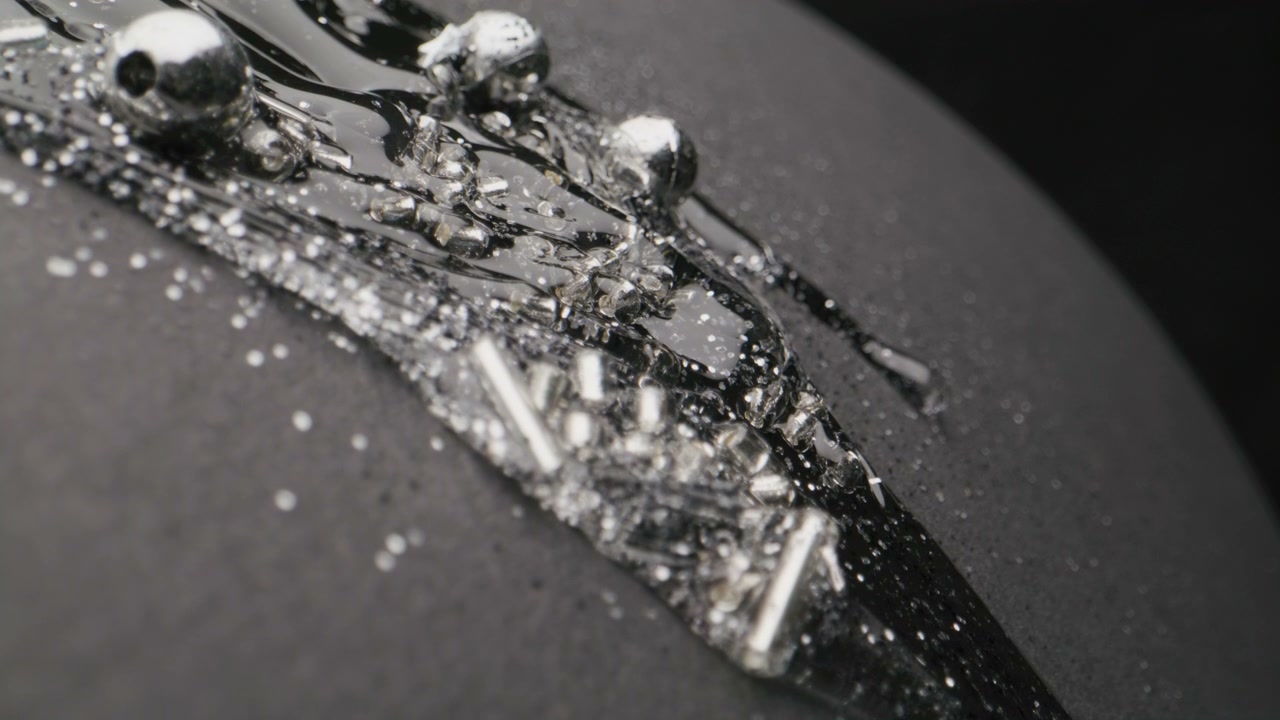 Silver Glitter and Beads Flowing on Black Surface