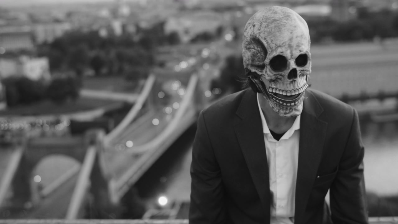 Skull Mask Figure on Rooftop Overlooking City