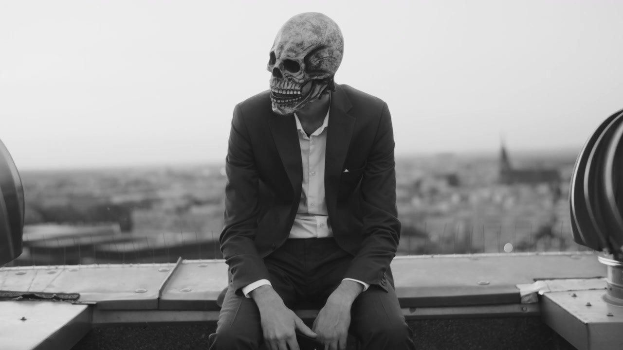 Person in Skull Mask Using Phone on Rooftop