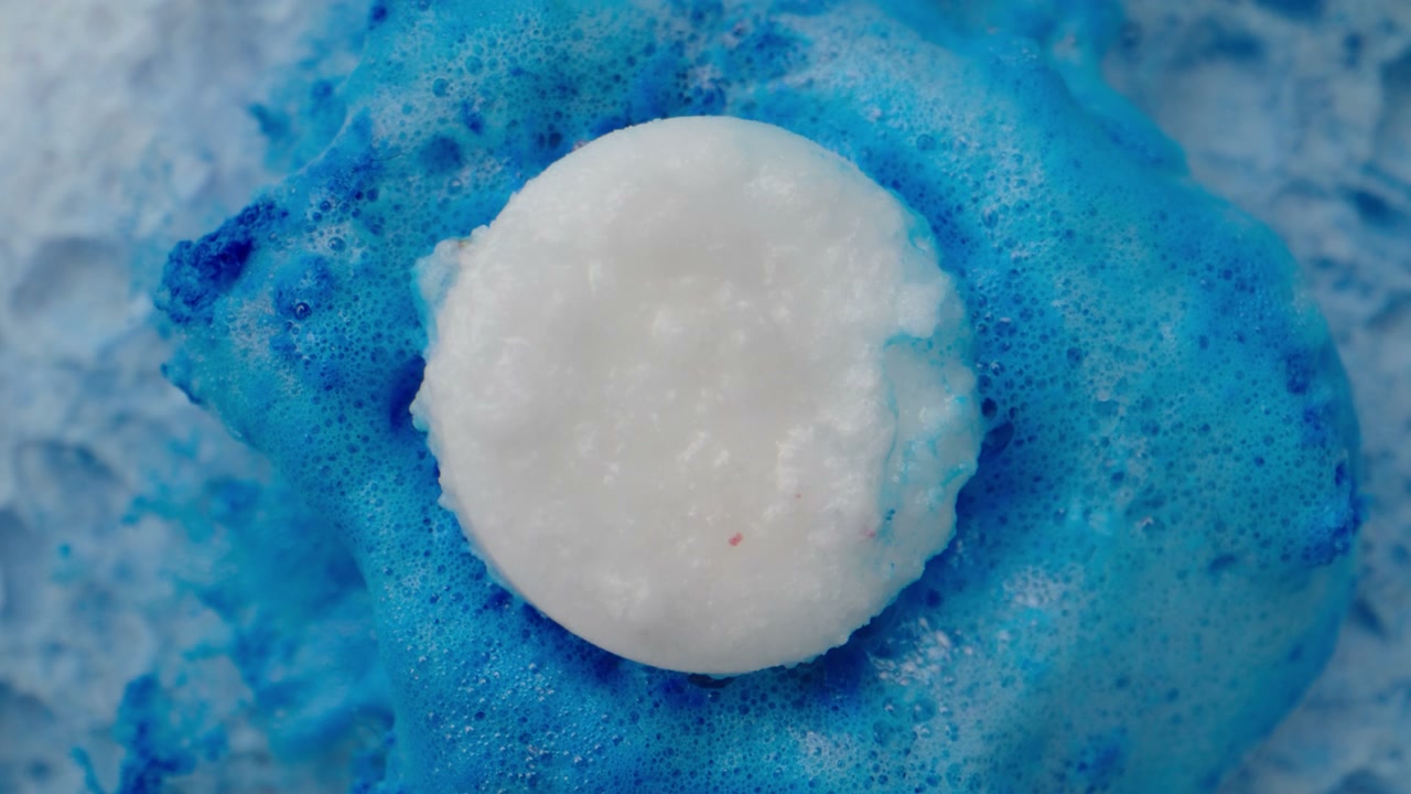 White Tablet Dissolving in Blue Foam