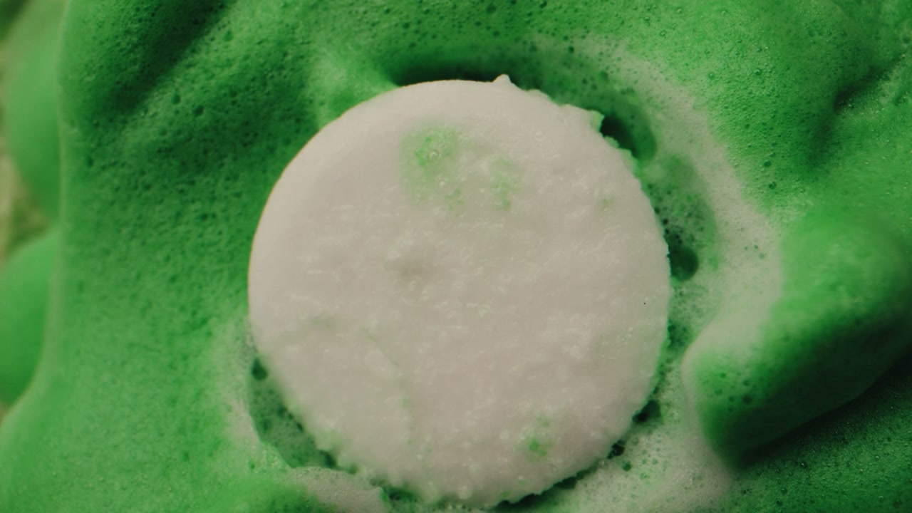 White Pill Dissolving in Green Foam
