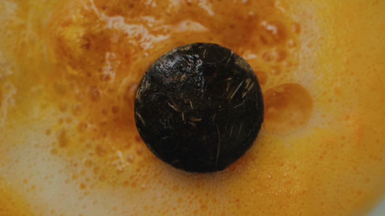 Dark Tablet Fizzing in Orange Liquid