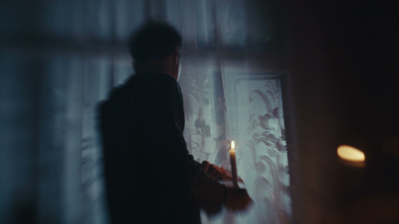 Man Performing Ritual with Candle in Dark Room