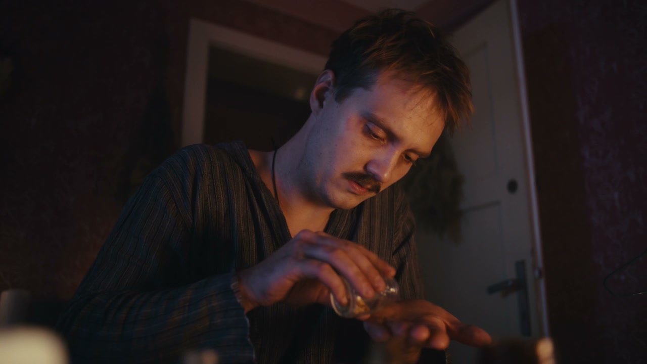 Man Performing Ritual with Small Objects by Candlelight