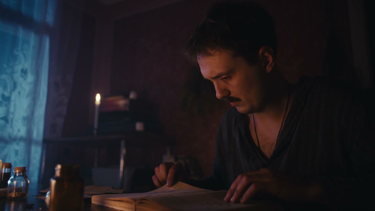 Man Studying Ancient Book in Dark Room