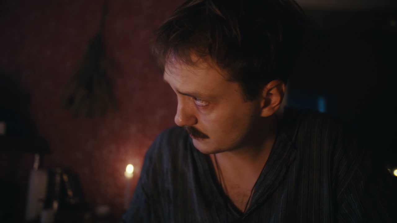 Man Holding Bottle in Candlelit Room