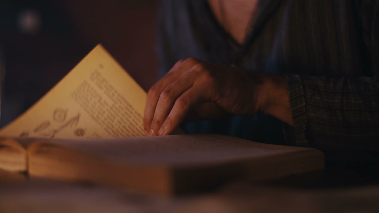 Hands Turning Pages of Old Book