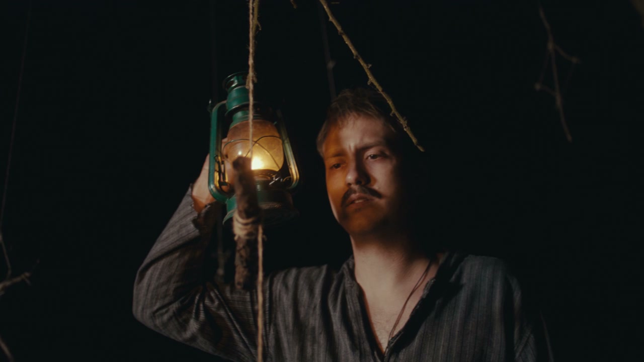 Man Holding Lantern in Dark Ritual Space