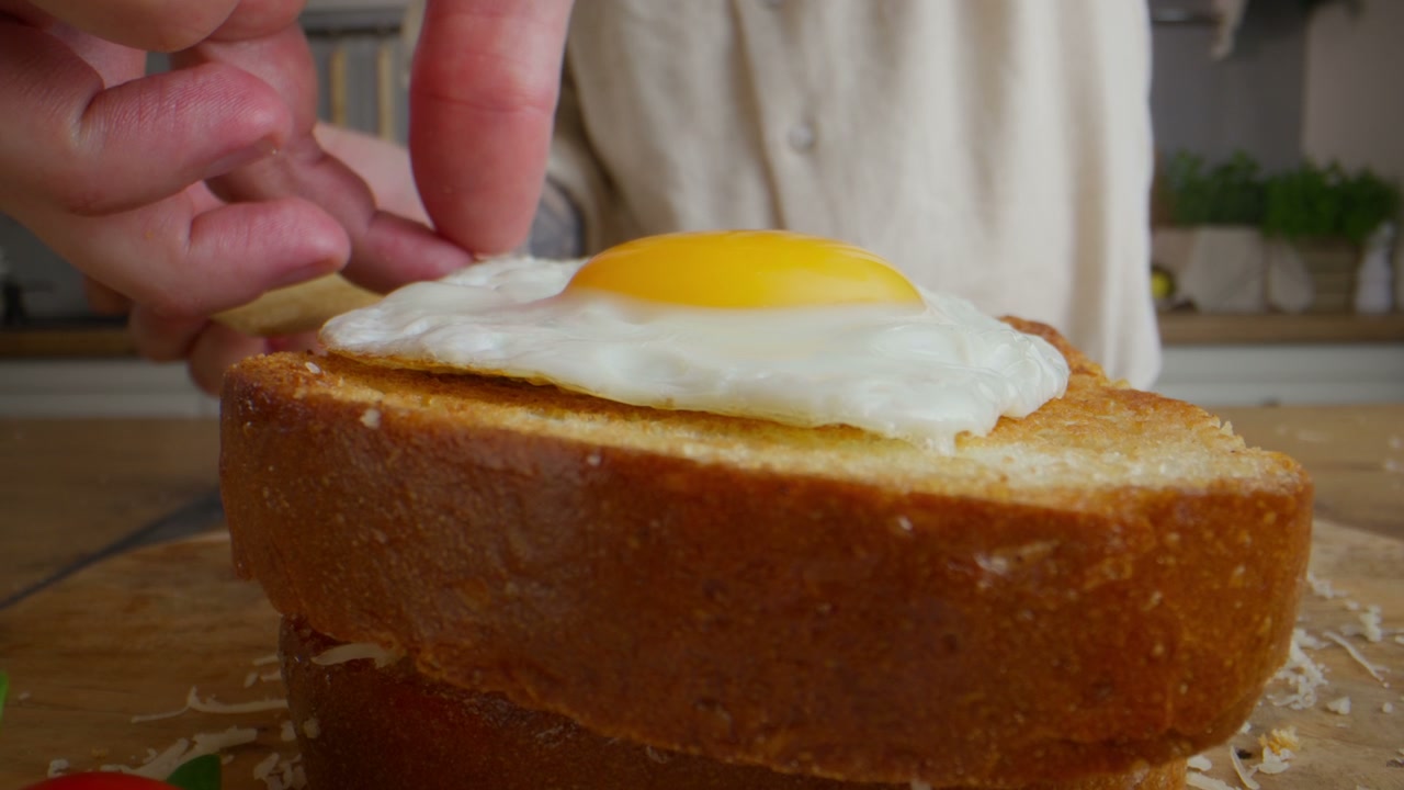 Hands Adjusting Fried Egg on Toast