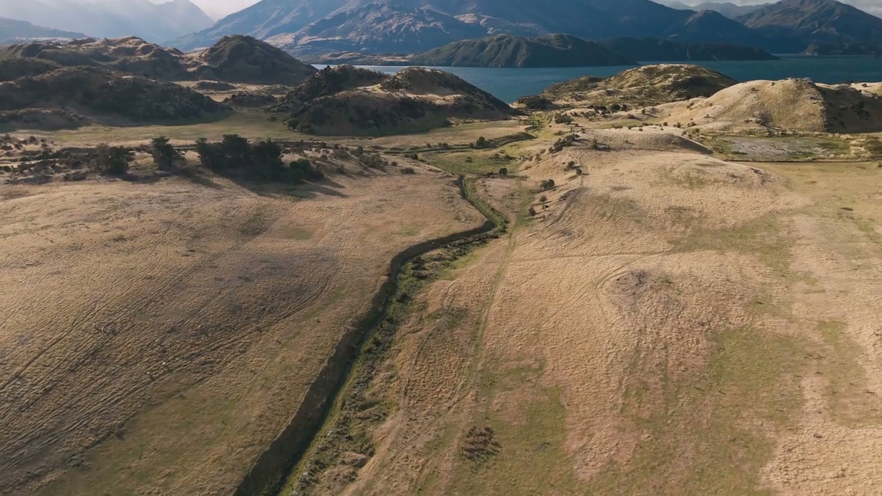 Aerial Landscape of Dry Fields, Hills, and Lake