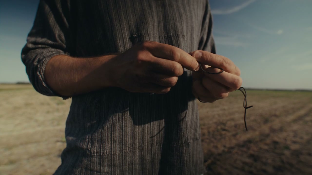 Person Tying Knot in Dry Field