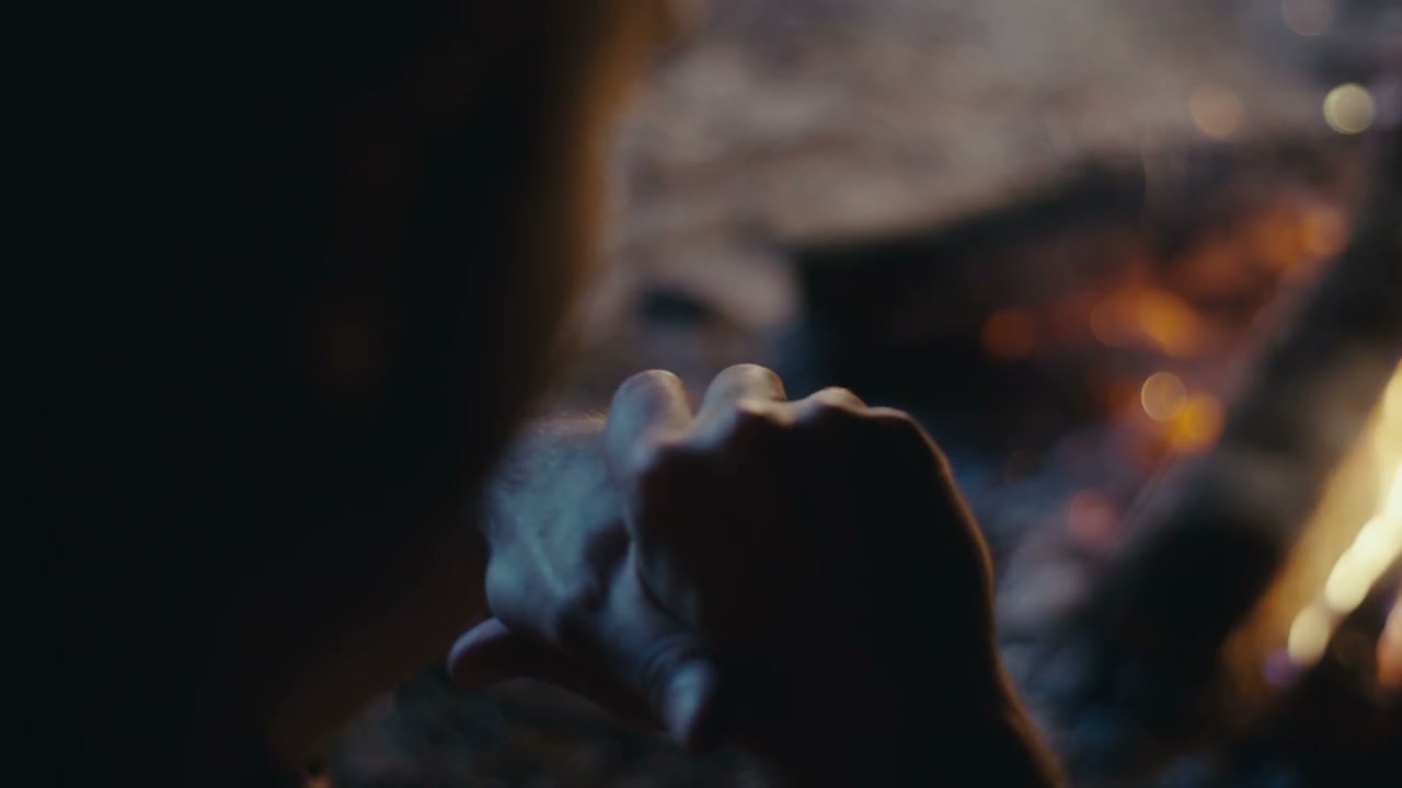 Man Removing Ring by Campfire Light