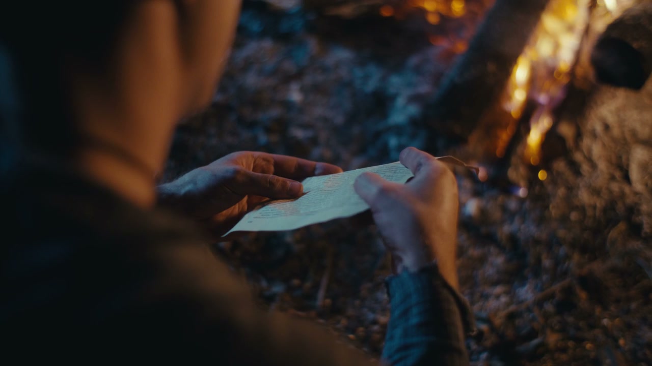 Man Burning Letter in Campfire