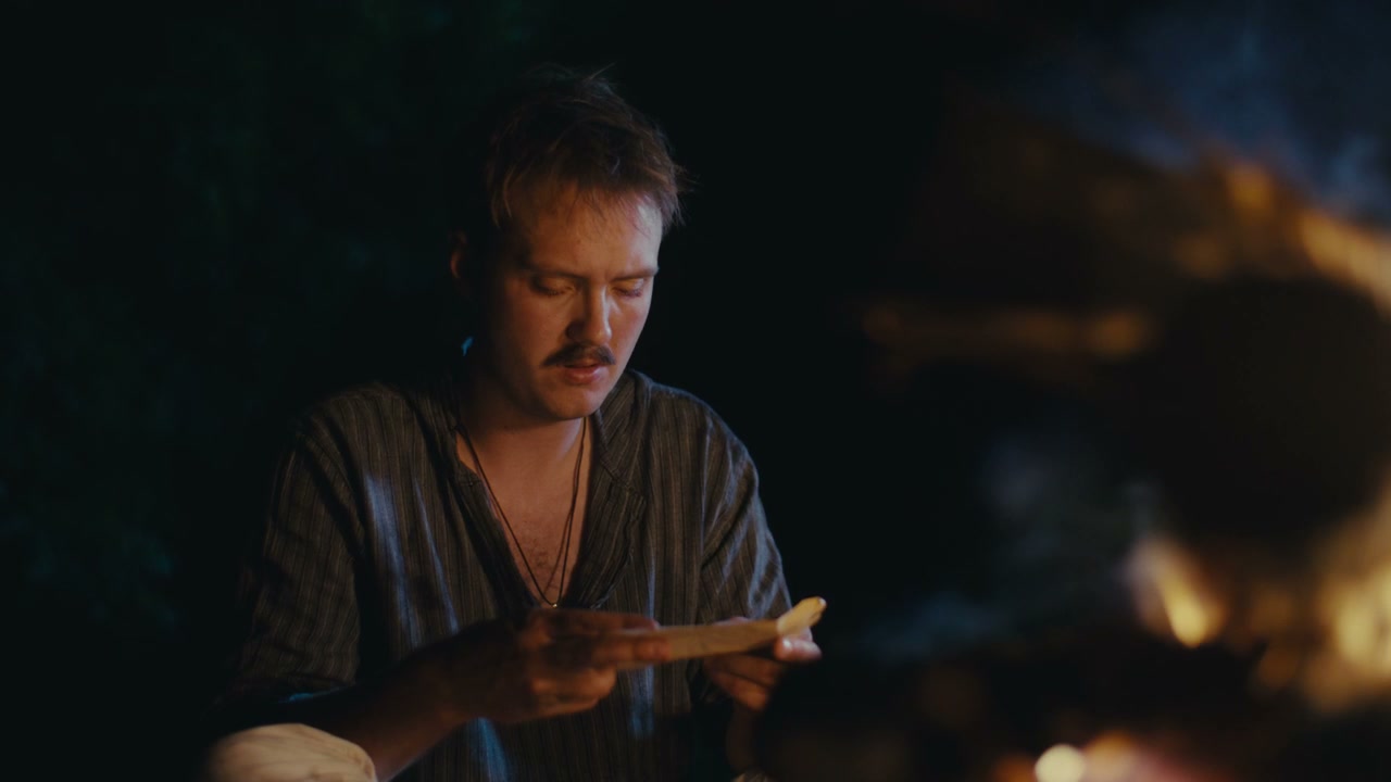Pensive Man Holds Paper By Campfire At Night