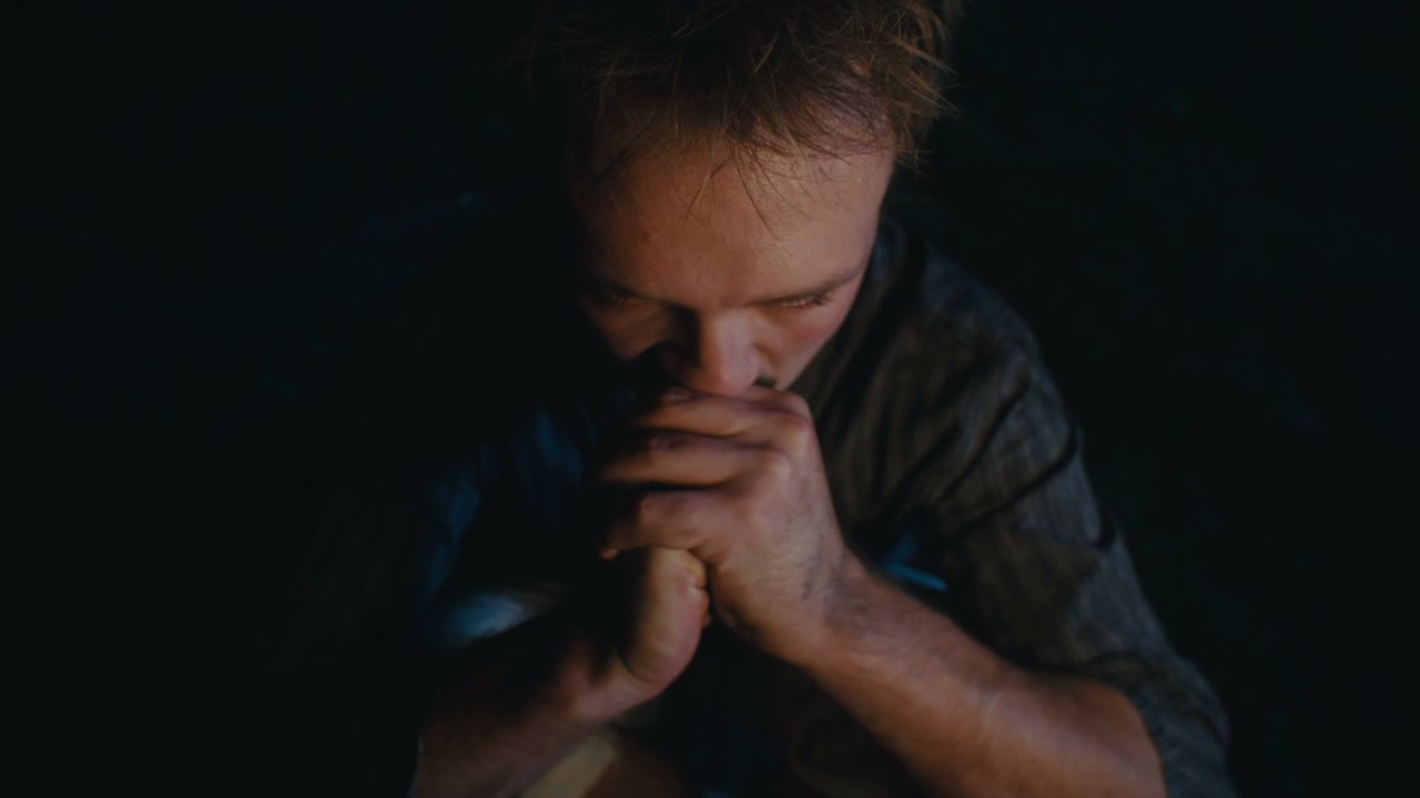 Distressed Man Huddling by Firelight at Night