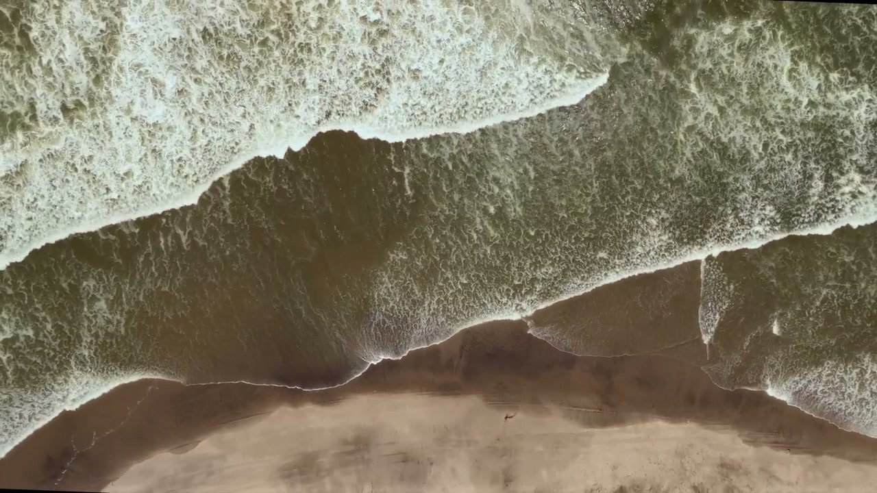 Aerial View of Waves Breaking on Dusty Coast