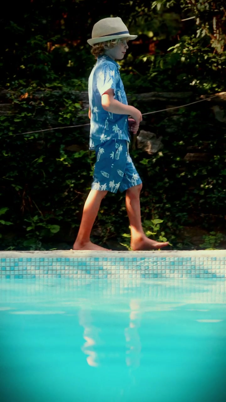 Boy in Sunhat Walking Poolside